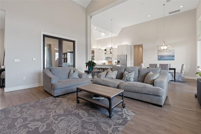 living room with visible vents, high vaulted ceiling, baseboards, and wood finished floors