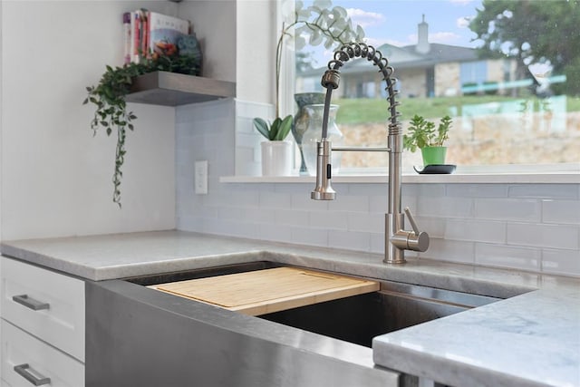 room details with decorative backsplash, white cabinets, a sink, and open shelves