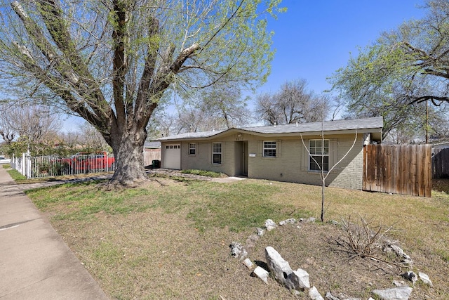 view of front of home featuring a front yard, an attached garage, fence, and brick siding