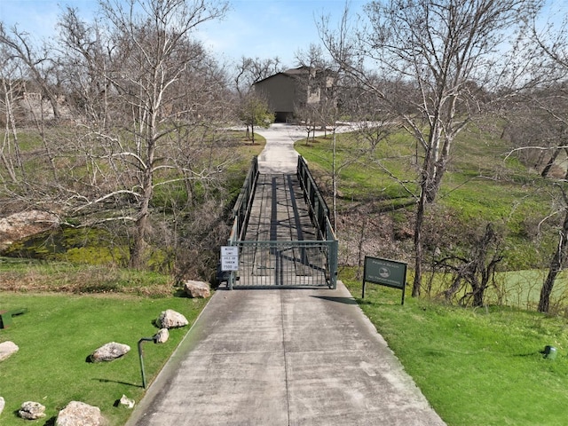 exterior space featuring concrete driveway, a gate, and a lawn