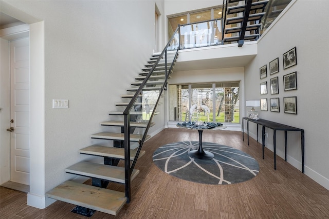 staircase with baseboards, a high ceiling, and wood finished floors