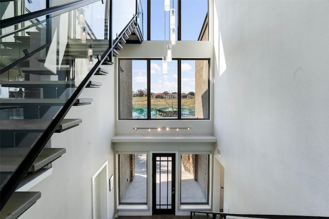 stairs with visible vents, a healthy amount of sunlight, and a high ceiling