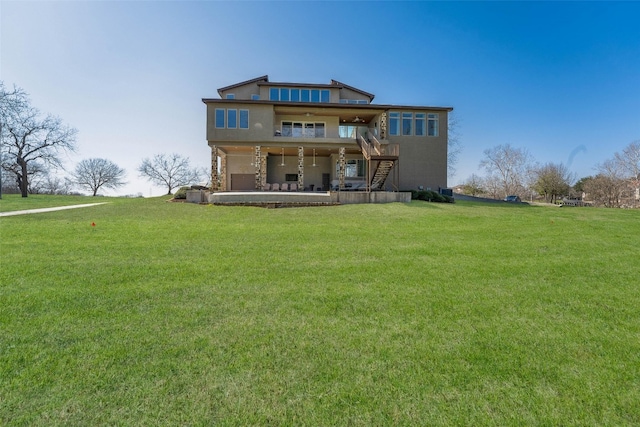 rear view of property featuring a patio area, stairway, a lawn, and a garage