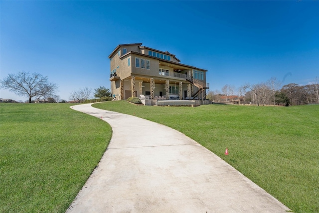 back of house featuring a balcony, a lawn, and stucco siding