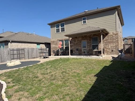 rear view of property featuring a patio, a lawn, and a fenced backyard