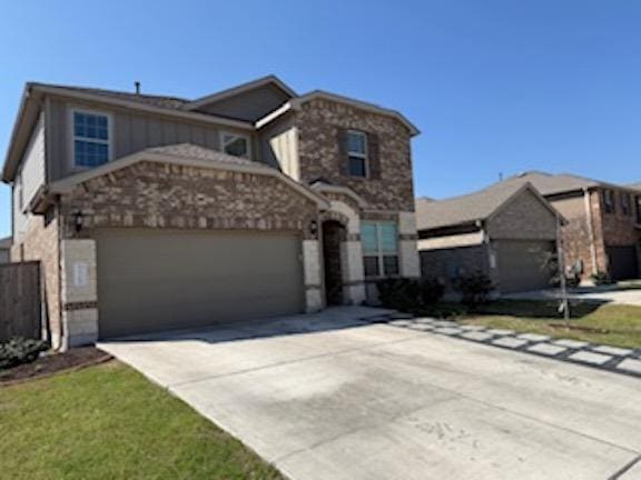 traditional-style house featuring concrete driveway, a garage, and stone siding