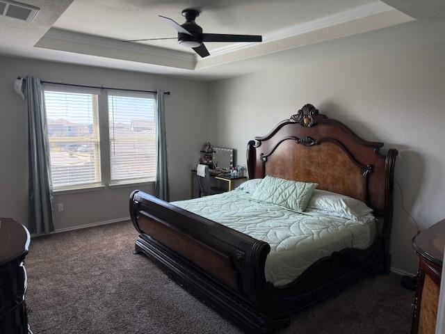 bedroom featuring visible vents, baseboards, carpet, a raised ceiling, and a ceiling fan