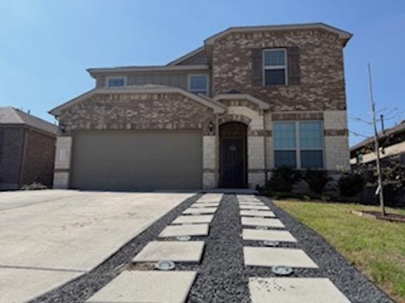 view of front of property featuring stone siding, driveway, and an attached garage