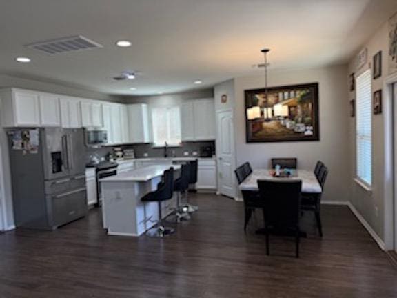 kitchen with a breakfast bar area, white cabinets, visible vents, and appliances with stainless steel finishes