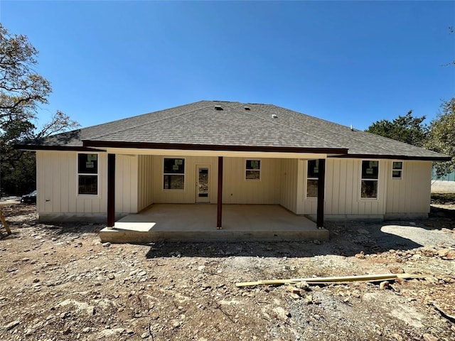 back of house with roof with shingles and a patio area