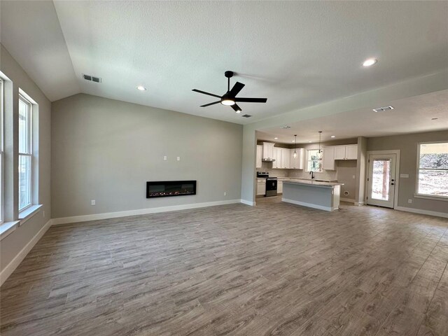 15 Persimmon Dr, Wimberley, TX 78676 - unfurnished living room with wood finished floors, ceiling fan, baseboards, a sink, and vaulted ceiling