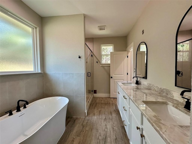 15 Persimmon Dr, Wimberley, TX 78676 - bathroom featuring a stall shower, a freestanding tub, double vanity, wood finished floors, and tile walls