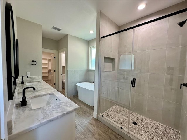 15 Persimmon Dr, Wimberley, TX 78676 - full bath with double vanity, a stall shower, a freestanding tub, wood finished floors, and tile walls