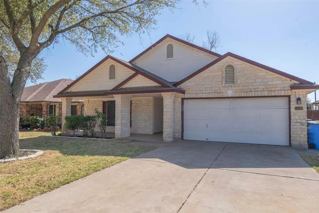 view of front of property featuring stone siding, driveway, a front lawn, and a garage