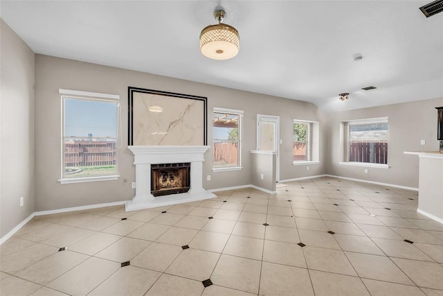 unfurnished living room with light tile patterned flooring, visible vents, a fireplace with raised hearth, and baseboards