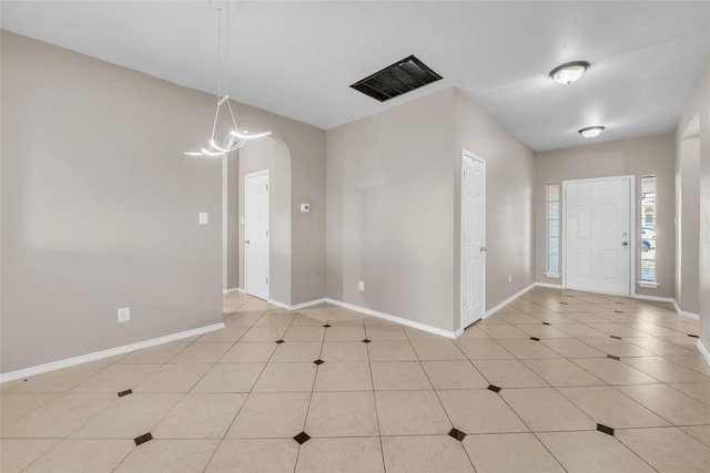 foyer with visible vents, light tile patterned flooring, arched walkways, and baseboards