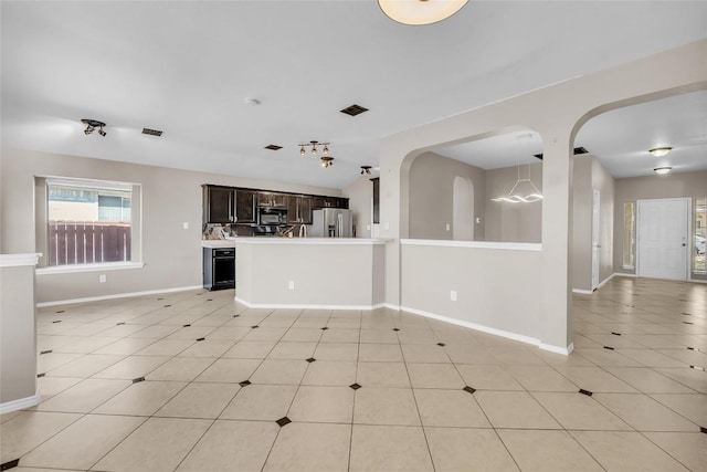 unfurnished living room with light tile patterned floors, arched walkways, and baseboards