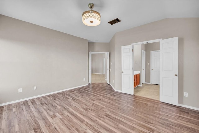 unfurnished bedroom with vaulted ceiling, light wood-style floors, visible vents, and baseboards