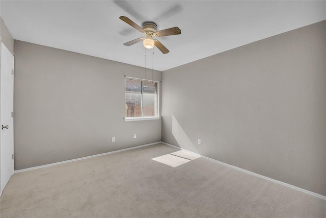 carpeted spare room with a ceiling fan and baseboards