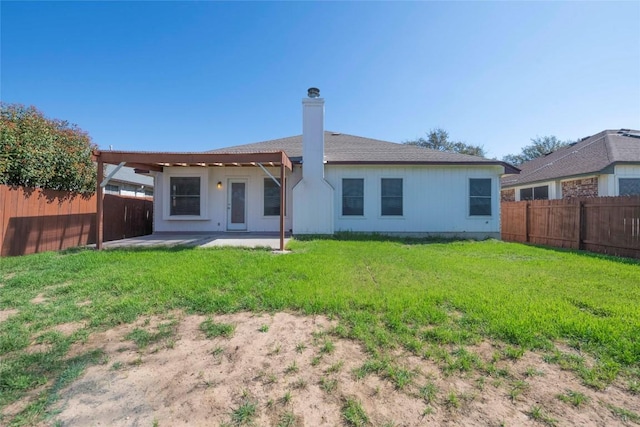 back of property with a patio area, a fenced backyard, a lawn, and a chimney