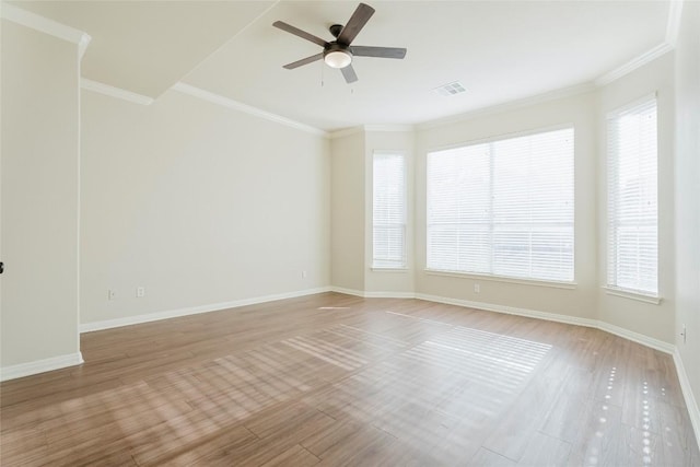 spare room with visible vents, light wood-style floors, ornamental molding, and a ceiling fan