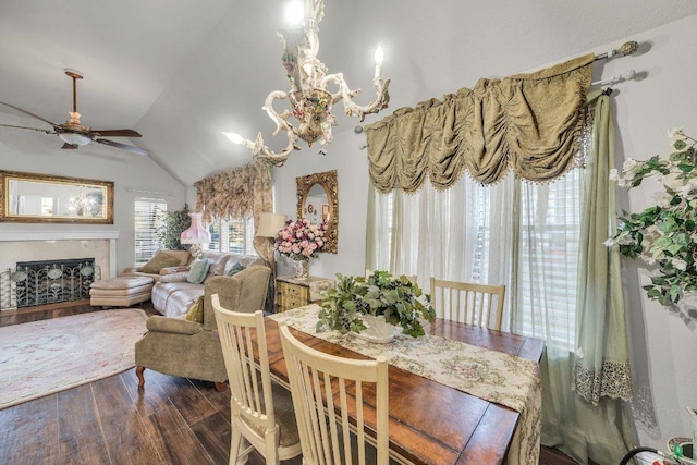 dining area featuring wood finished floors, vaulted ceiling, a ceiling fan, and a premium fireplace