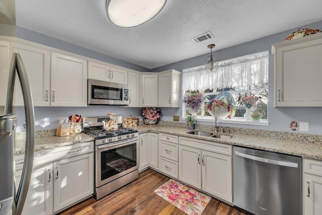 kitchen with a sink, a textured ceiling, stainless steel appliances, visible vents, and dark wood-style flooring