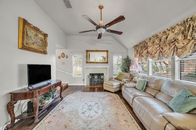 living room with vaulted ceiling, ceiling fan, visible vents, a fireplace, and wood finished floors