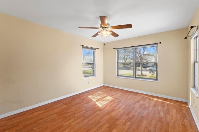 spare room with light wood-type flooring, baseboards, and ceiling fan