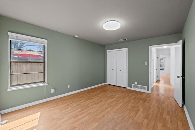 unfurnished bedroom with baseboards, visible vents, a closet, and light wood-type flooring