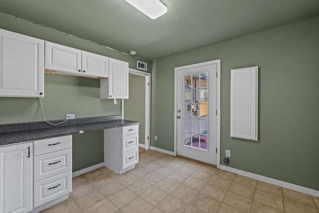 kitchen featuring white cabinetry, dark countertops, baseboards, and visible vents