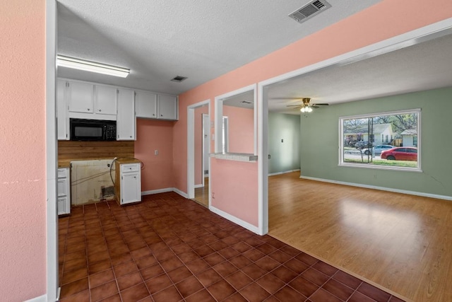 kitchen with visible vents, ceiling fan, black microwave, a textured ceiling, and white cabinetry