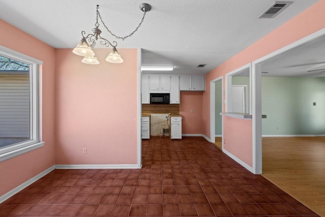 kitchen with white cabinetry, baseboards, visible vents, and black microwave