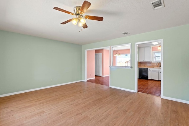 unfurnished living room featuring visible vents, baseboards, light wood-style floors, a ceiling fan, and a sink