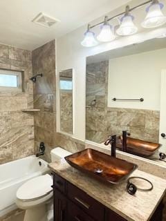 bathroom featuring vanity, visible vents, decorative backsplash, bathing tub / shower combination, and toilet