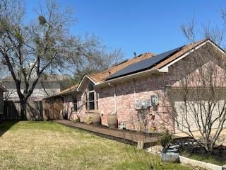 view of property exterior with a yard and roof mounted solar panels