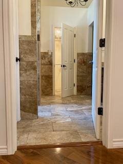 bathroom featuring a wainscoted wall, tile walls, and a chandelier