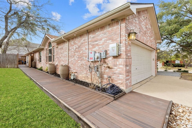 view of side of home featuring a lawn, fence, concrete driveway, a garage, and brick siding