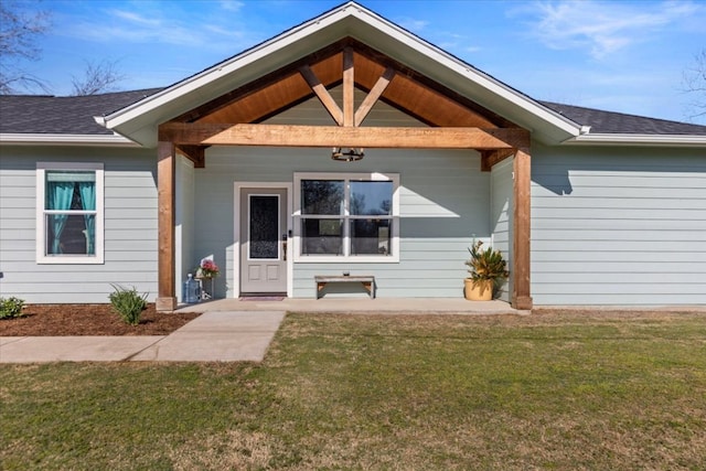 doorway to property with a yard and roof with shingles