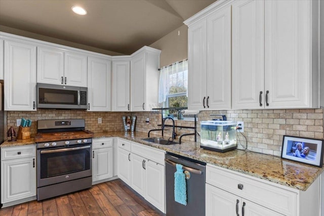 kitchen featuring dark wood-style floors, a sink, stainless steel appliances, white cabinets, and backsplash