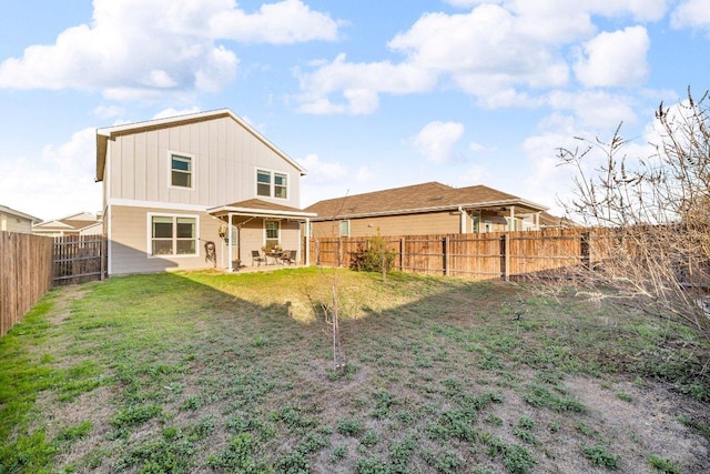 back of house featuring a patio area, a yard, a fenced backyard, and board and batten siding