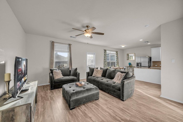 living area with baseboards, a ceiling fan, visible vents, and light wood-type flooring