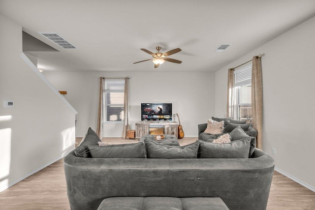 living room featuring a ceiling fan, visible vents, light wood finished floors, and baseboards