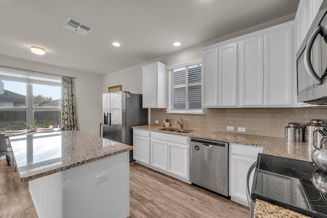 kitchen featuring tasteful backsplash, visible vents, light wood-style floors, stainless steel appliances, and a sink