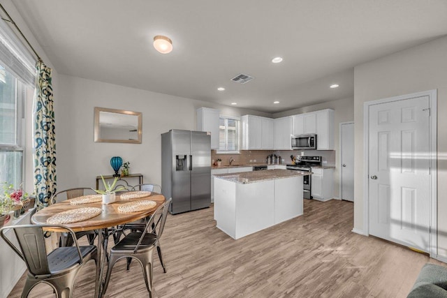 kitchen featuring light wood-type flooring, visible vents, a center island, white cabinetry, and stainless steel appliances