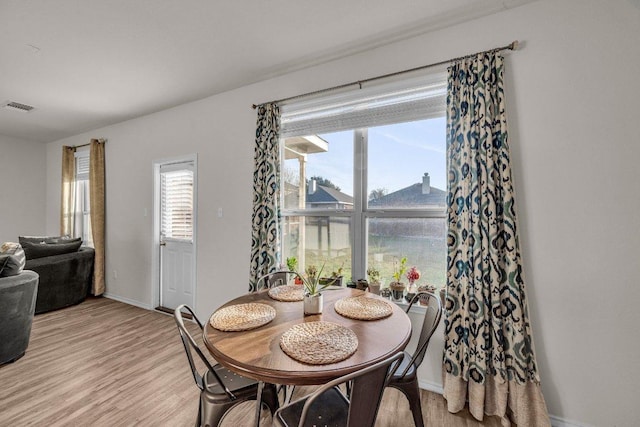 dining area with visible vents, light wood-style flooring, and baseboards