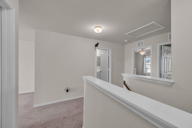 hall featuring visible vents, carpet floors, baseboards, and an upstairs landing