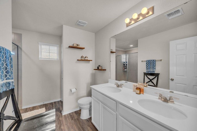 bathroom with a stall shower, visible vents, and a sink