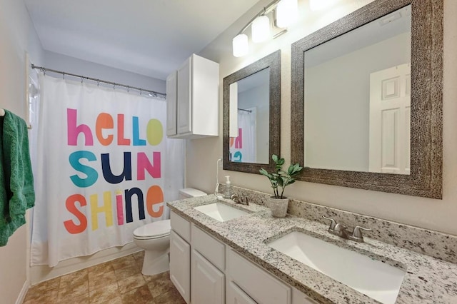 bathroom with double vanity, toilet, and a sink
