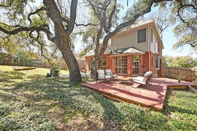 back of house with a deck, a yard, a fenced backyard, and brick siding